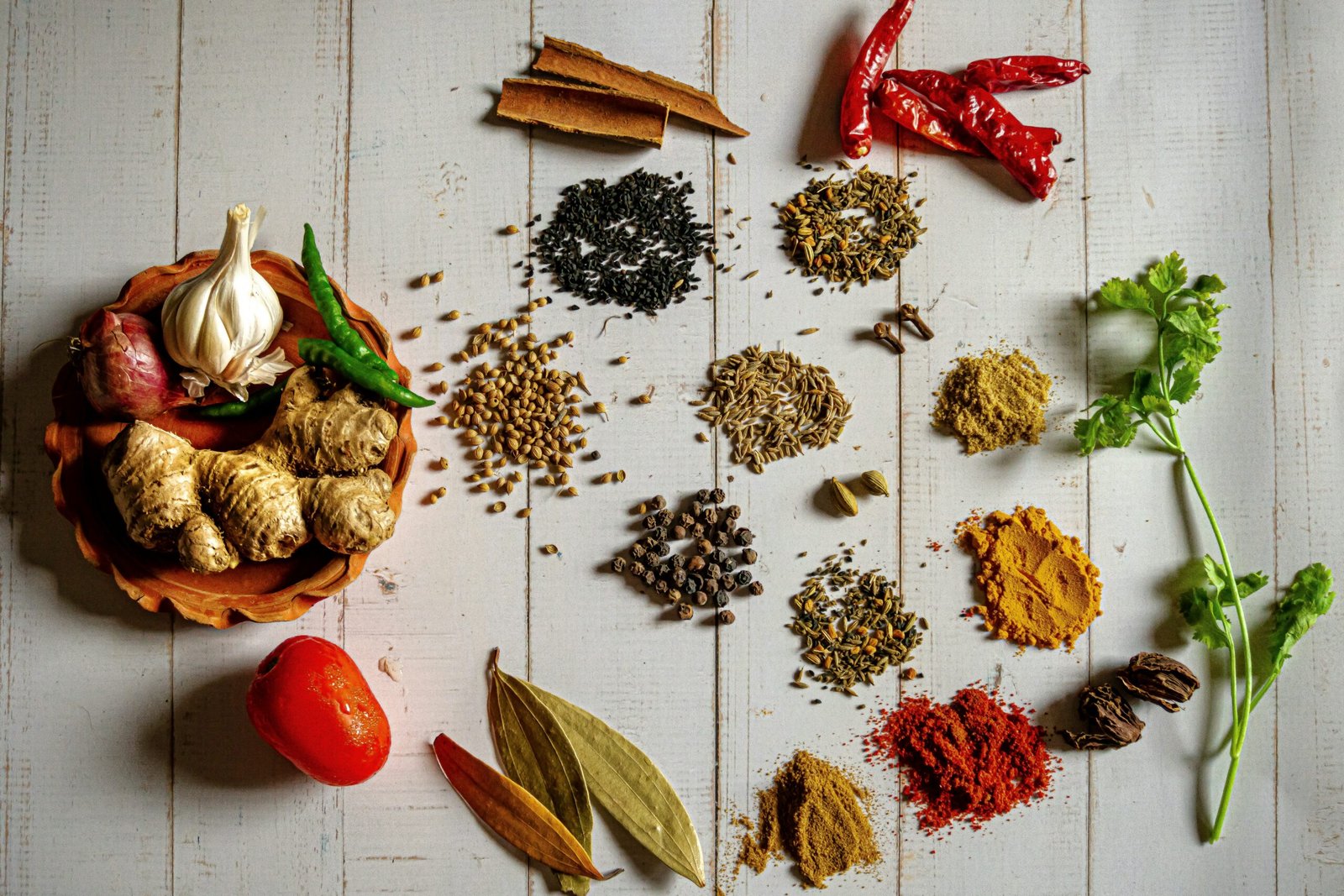 Colourful Indian spices including turmeric, chilli, cumin and cardamom arranged in bowls